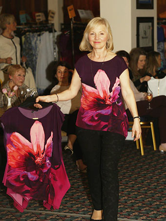 model in flower top walking down the aisle holding another top