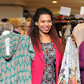 Smiling model at event holding up two patterned tops