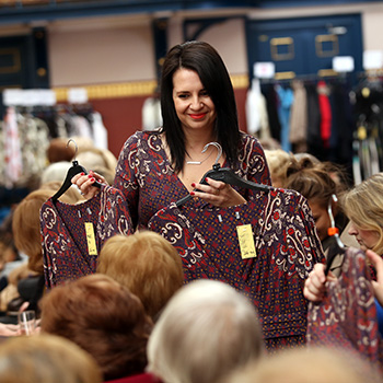 Model on catwalk carrying two extra items of the top she is wearing